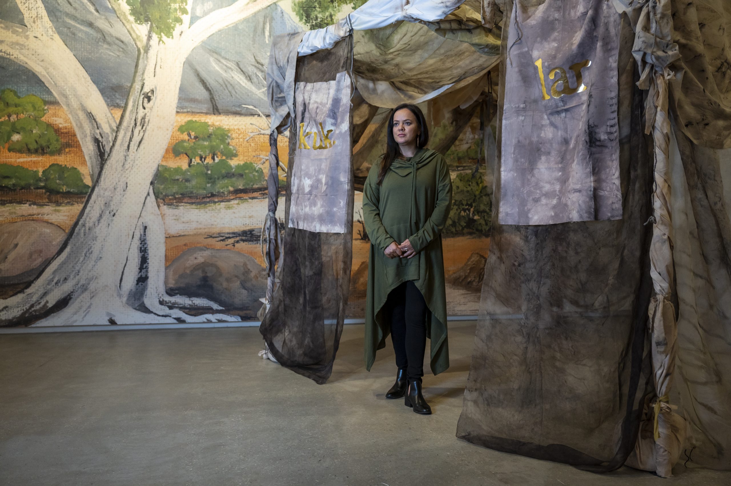 Stacie Piper stands at the entrance of Paola Balla's artwork