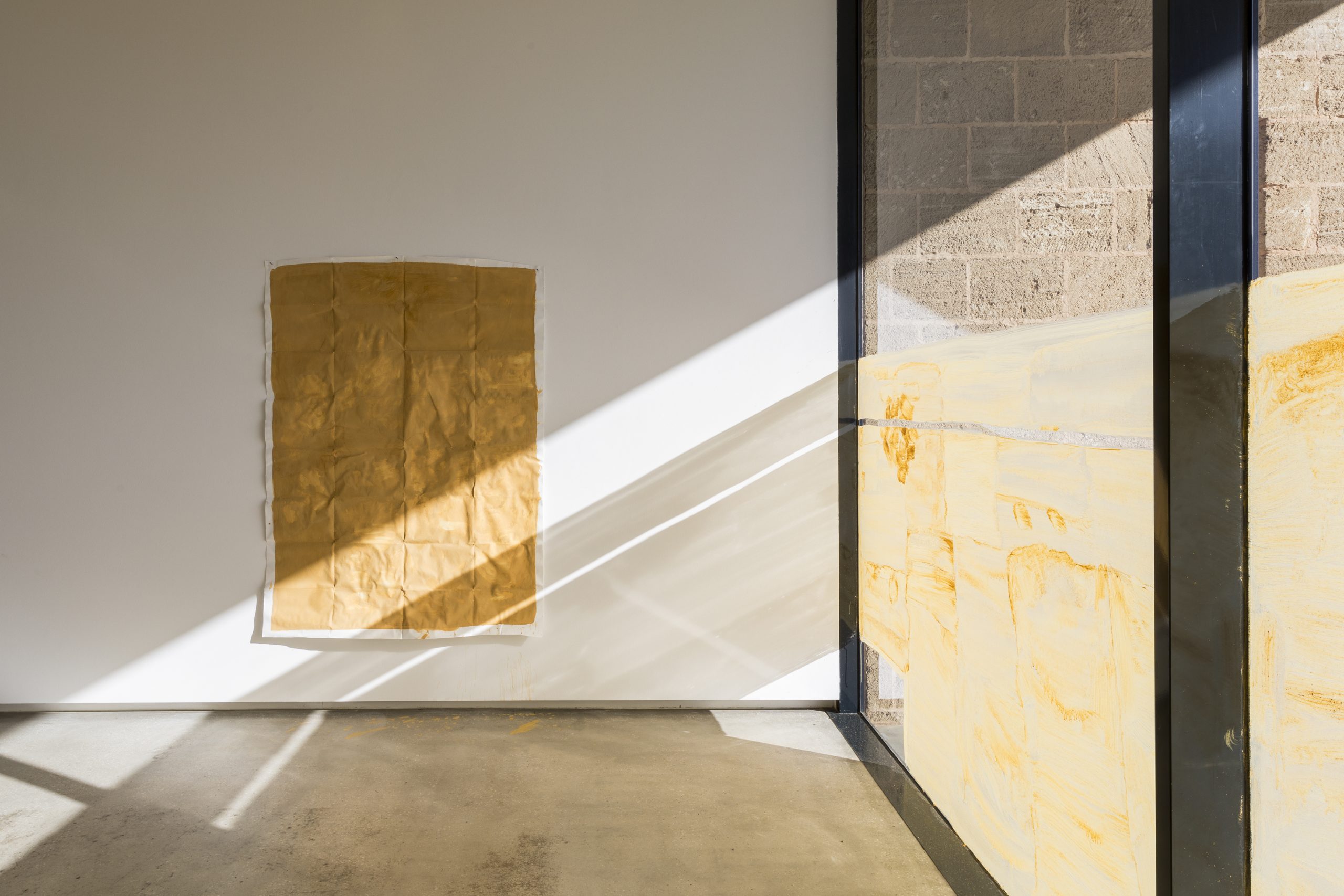 an art installation of ochre on paper and glass