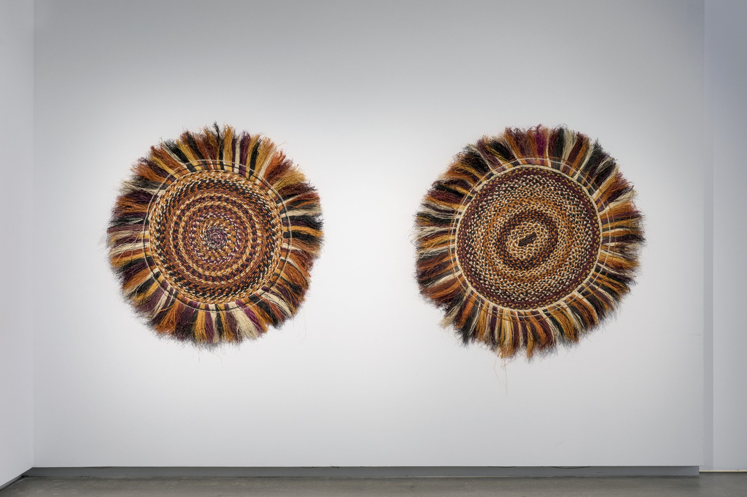 two woven artworks on a gallery wall